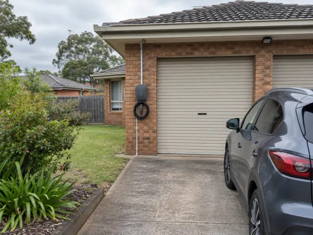 Wall-mounted EV charger beside a brick garage and driveway in Cameron Park
