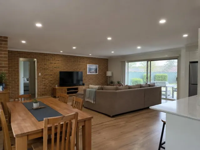 Living and dining room with flush ceiling downlights, brick feature wall and sliding doors in Edgeworth